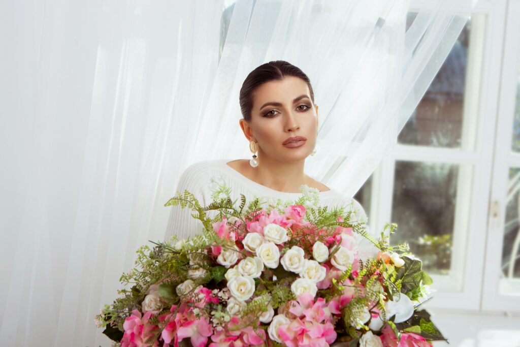 pexels-photo-7083263-7083263 Beautiful woman with a bouquet of pink and white flowers indoors, exuding elegance and charm.